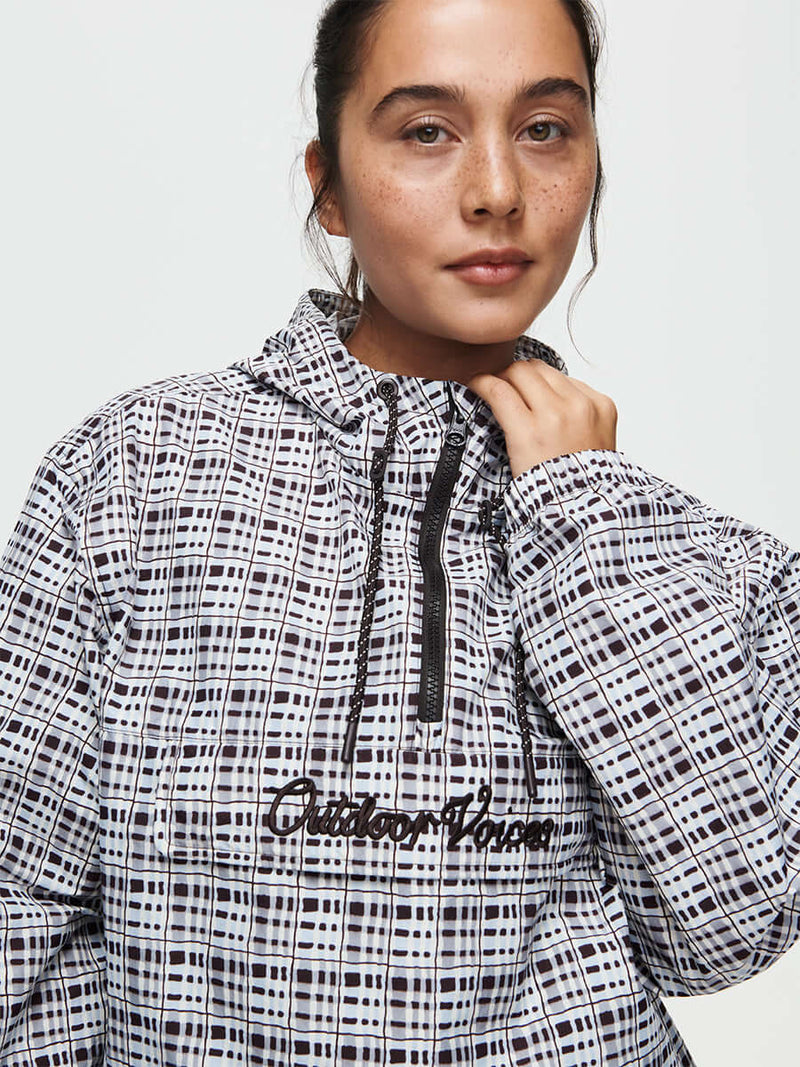 Fashionable woman wearing a windbreaker with a checkered print, showcasing its stylish look and outdoor appeal.