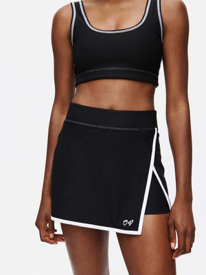 Model wearing Court Skort 2.5" with hand-embroidered signature and silicone gripper band in black.