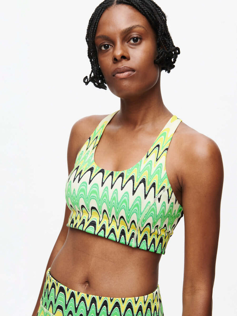 Model showcasing the vibrant Doing Things Bra CL in green and black wavy pattern.