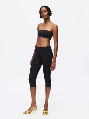 Model showcasing the sleek Grass Capri leggings in black paired with a black strapless top.