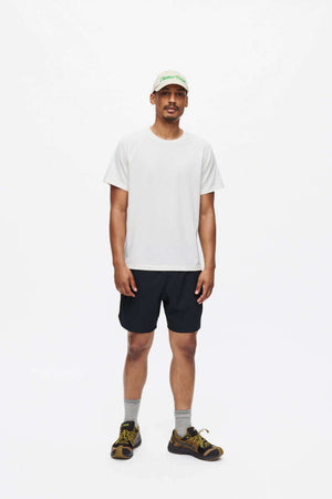 Man wearing High Stride 7" Short with Pockets CL and a white shirt, captured in a studio setting.