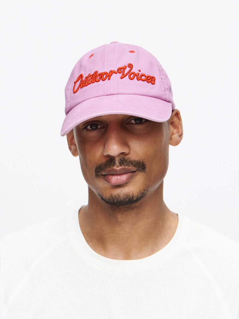 Washed Hat CL worn by a man, featuring a pink design with bold red lettering.