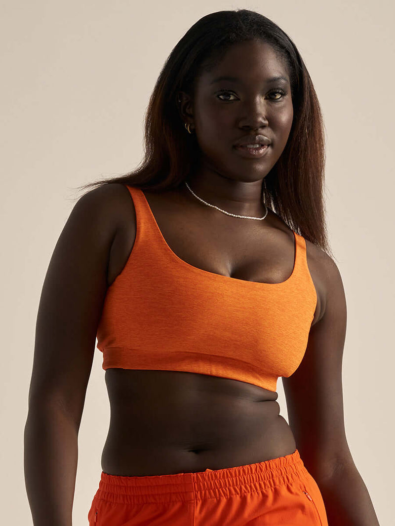 Model wearing the stylish Double Time Bra CL in vibrant orange, showcasing comfort and support.