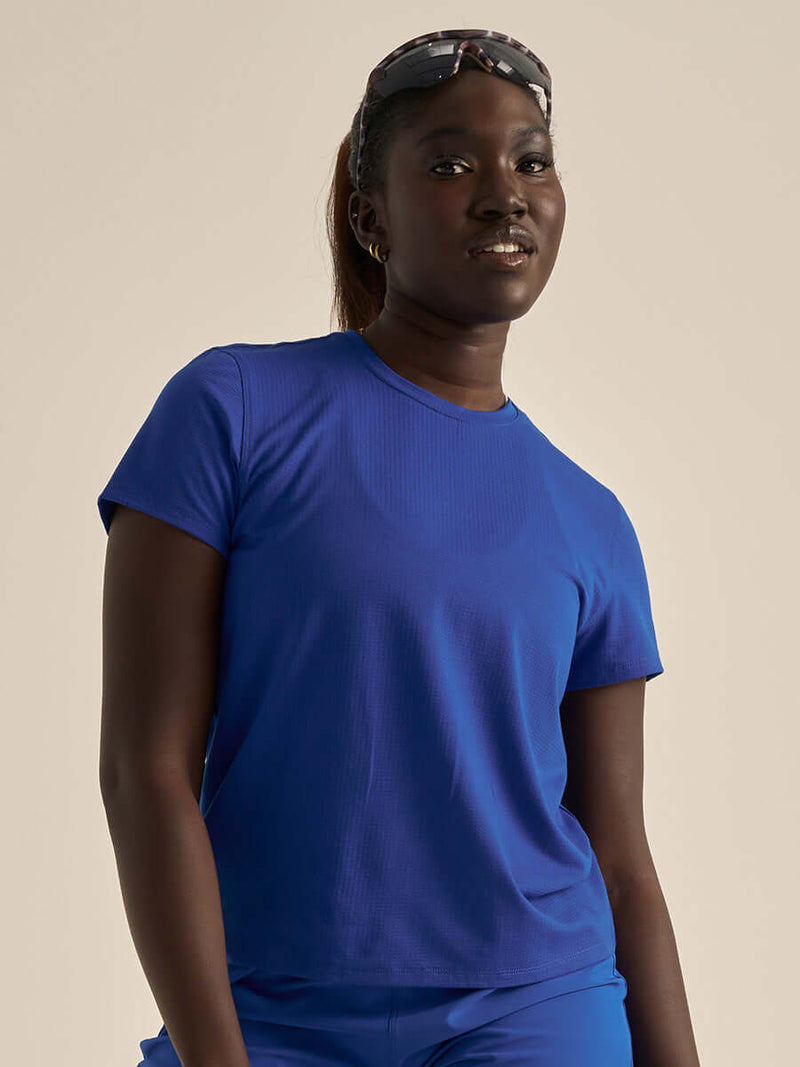 Model wearing ThinkFast Mesh Shortsleeve CL in vibrant blue, showcasing comfort and style for activewear.