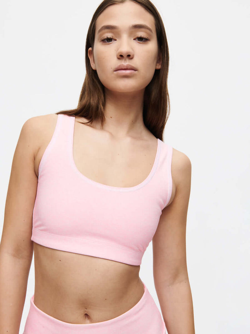 Model wearing the Orbit Bra in pink, showcasing its medium-impact design and soft-fit elastic band.