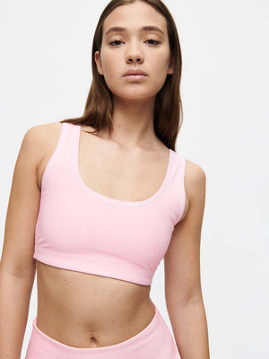Model wearing the Orbit Bra in pink, showcasing its medium-impact design and soft-fit elastic band.