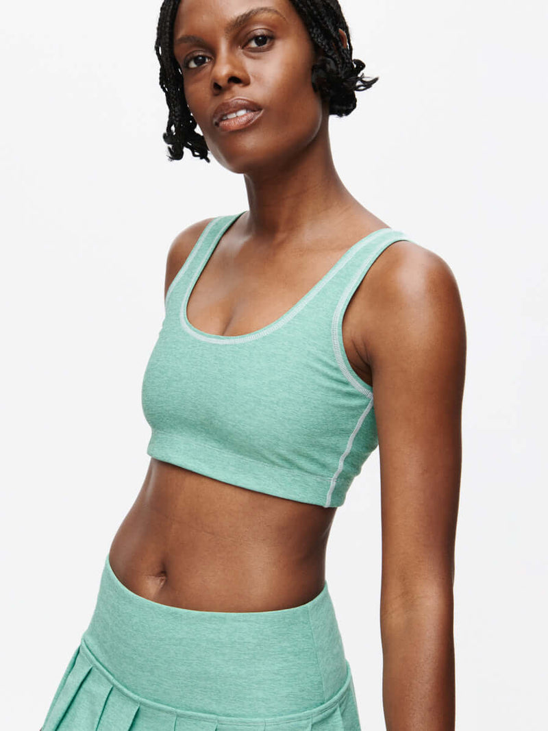 Model wearing the Orbit Bra in green, showcasing its soft-fit elastic band and textured fabric.