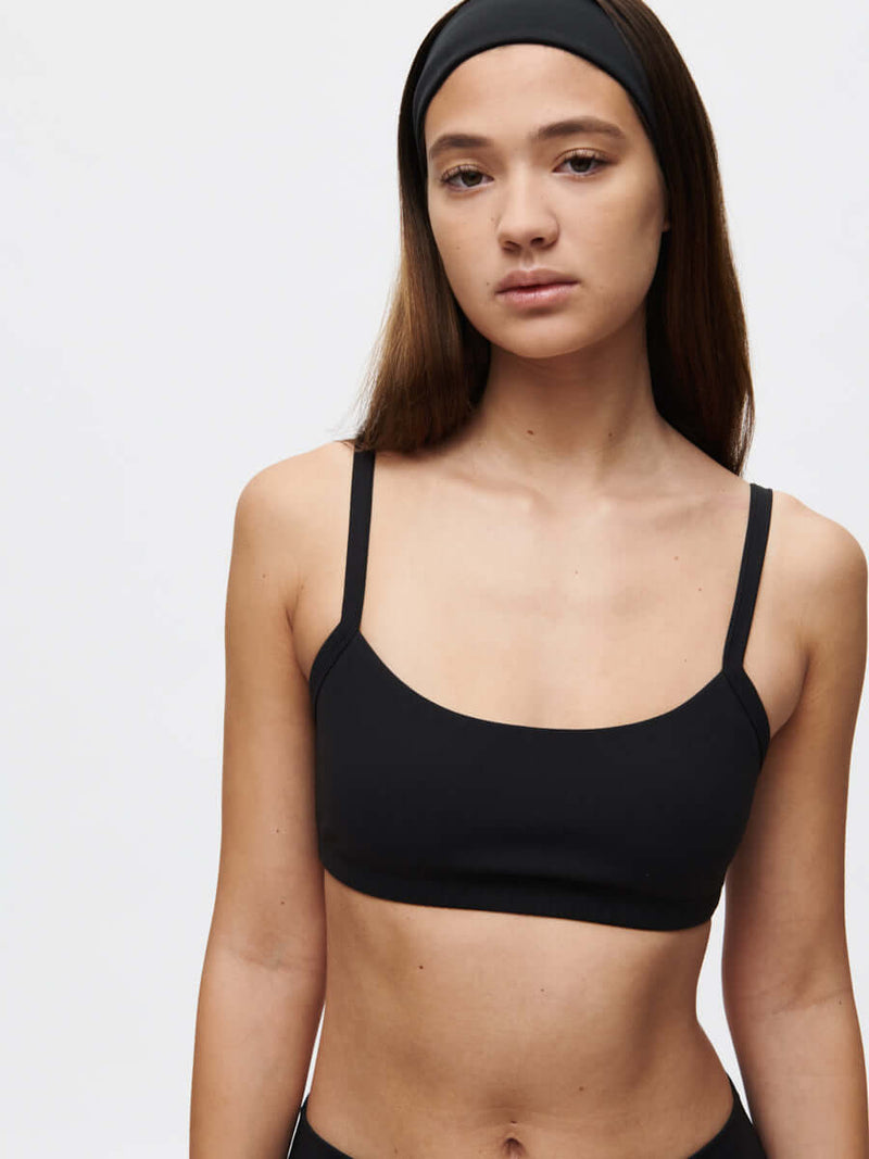 Model wearing the Solar Bra in black with adjustable straps and a sleek design.