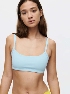Model wearing the Solar Bra in soft blue, showcasing adjustable straps and a comfortable elastic band.