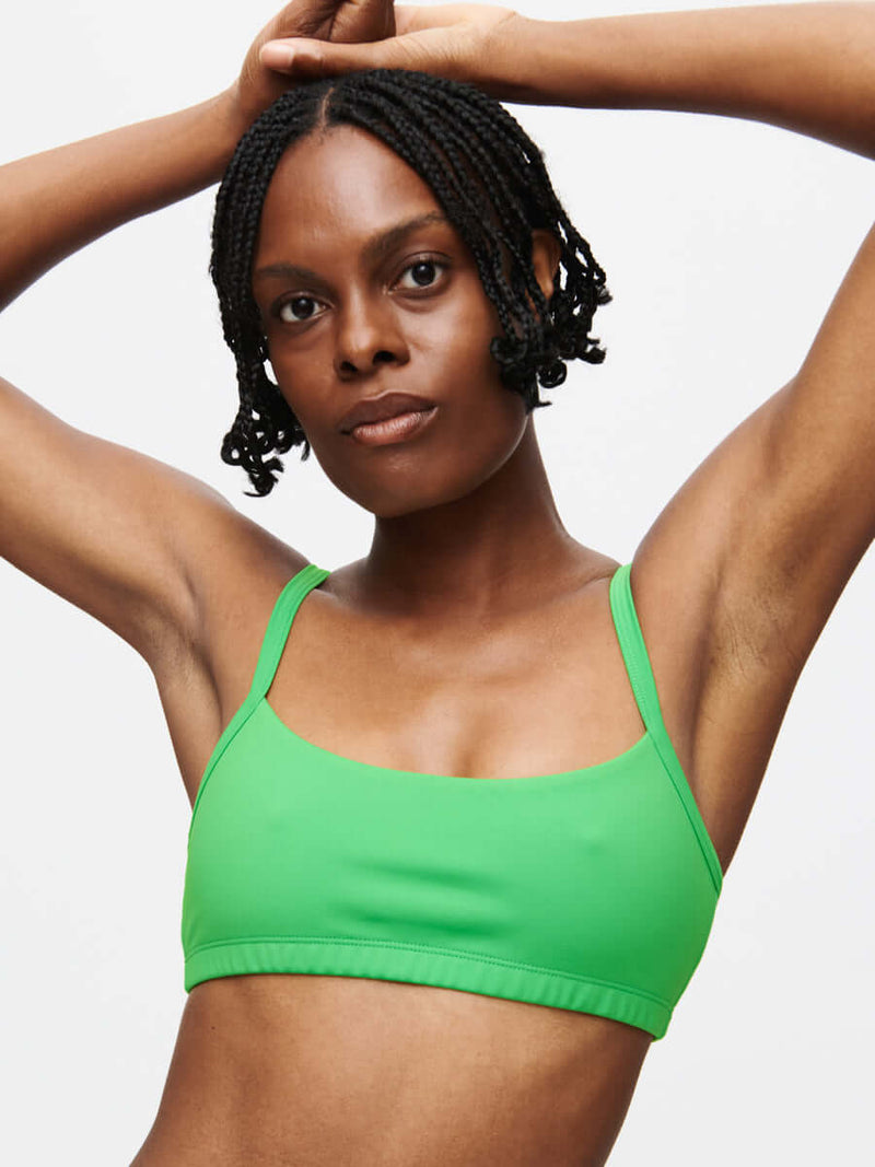 Model showcasing the stylish Solar Bra in vibrant green, featuring adjustable straps and a smooth texture.