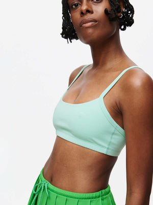 Model wearing the Solar Bra in mint color, featuring adjustable straps and soft elastic band for medium support.
