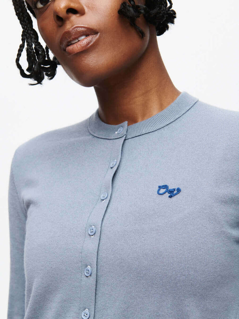 A model showcasing the Sugar Cardigan in soft cotton cashmere with an OV signature embroidery.