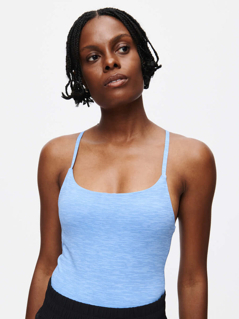 Model wearing a light blue TechSweat Move Free Tank CL, showcasing its sleek design and comfort.