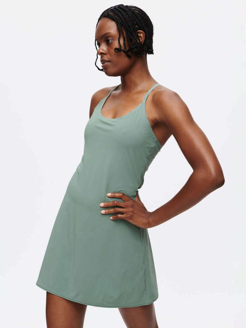 Model showcasing The Exercise Dress in green, featuring adjustable straps and a sporty, functional design.