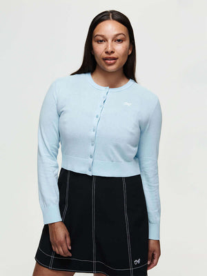 Model wearing a light blue Sugar Cardigan made of soft cotton cashmere, featuring hand-embroidered OV signature.