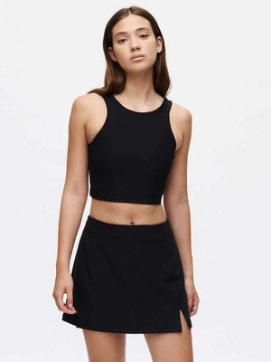 Model wearing a black crop top and Warmup 2.5" Skort, showcasing stylish activewear for performance sports.