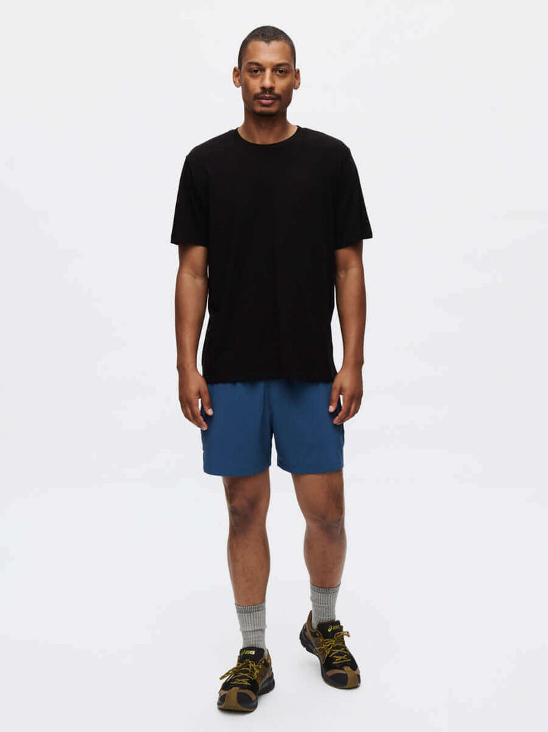 Man wearing Zephyr 5" Short with black t-shirt and casual shoes, showcasing a sporty look.